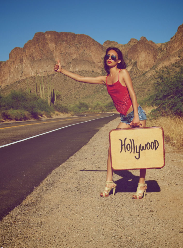 Girl by a road with Hollywood suitcase 