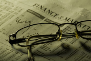 Business sectionin newspaper concept. Focus on glasses under green light